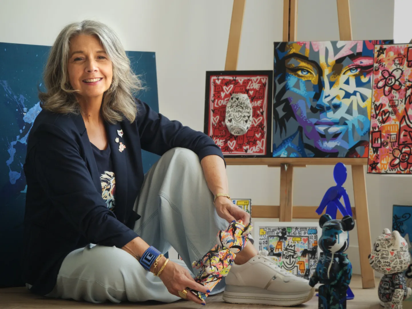 Crystelle Terrasson, assise parmi les peintures et sculptures qu’elle réunit pour Jukkai.